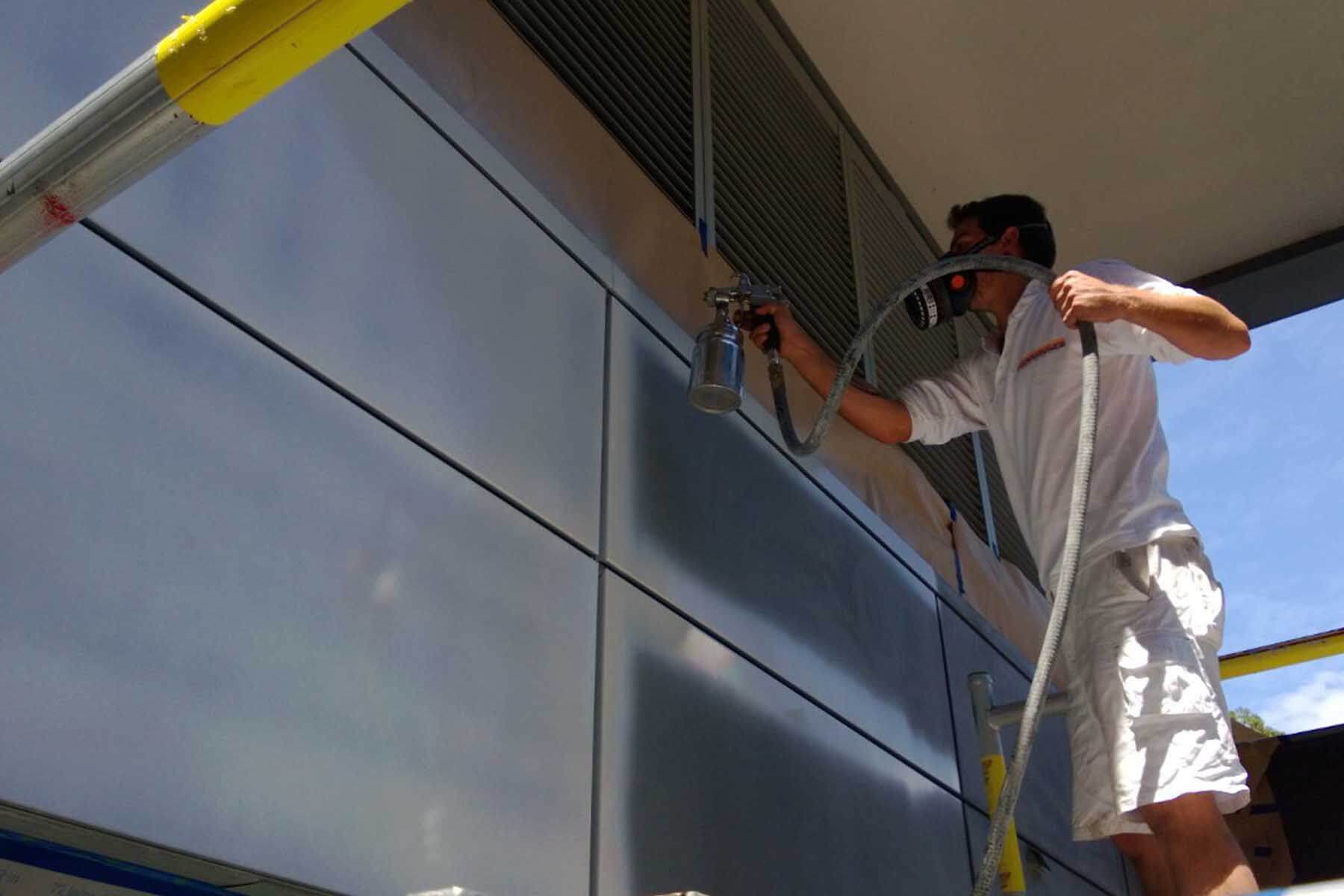 painting technician spraying painting exterior commercial building